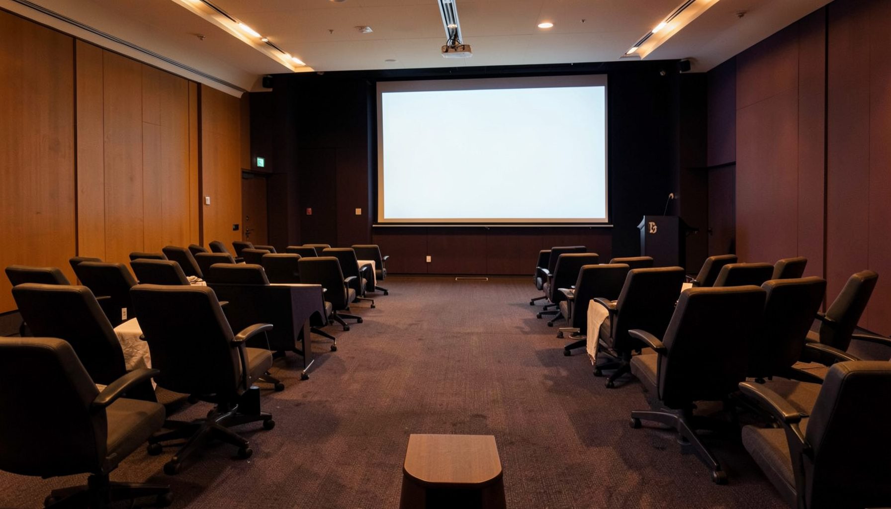 Wide conference room with rows of chairs and a presentation screen, warm amber and deep navy tones, professional atmosphere